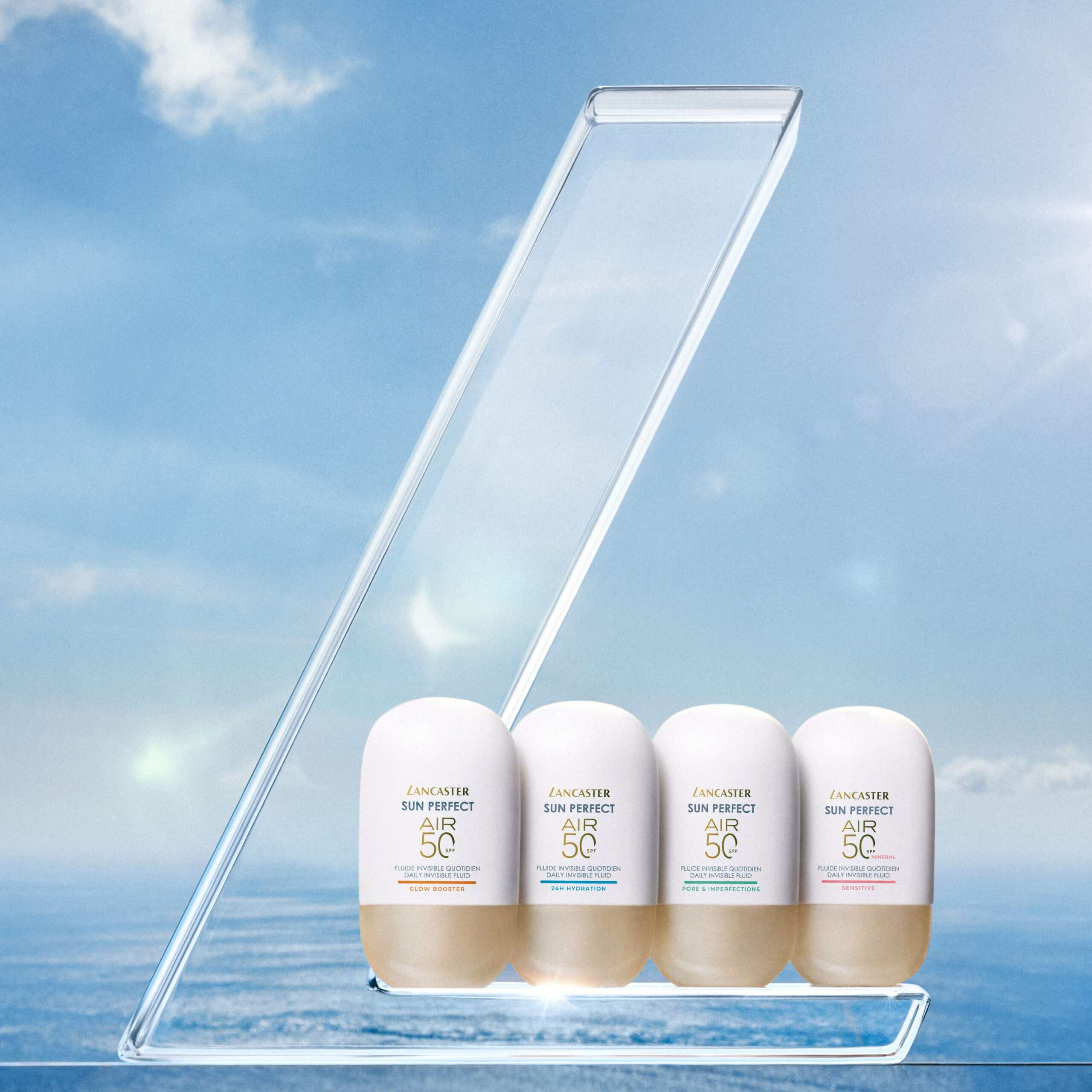Lancaster Sun Perfect Air SPF50 sunscreen collection with four bottles displayed against blue sky and sea background
